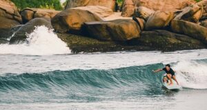 A surfer skillfully riding a wave along the Surf Sri Lanka East Coast, highlighting the area's excellent surf conditions and breathtaking natural scenery.